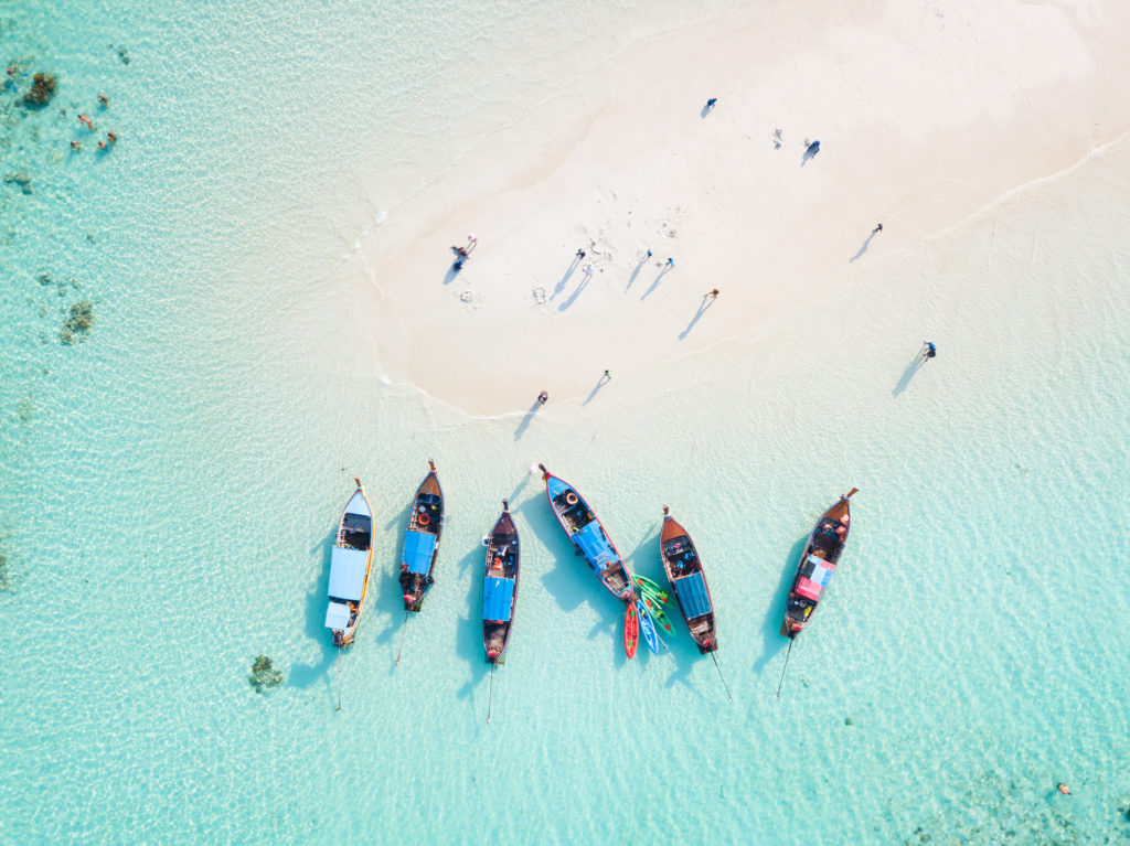Top view or aerial view of longtail boats on crystal clear water along the sand beach in Phuket Thailand